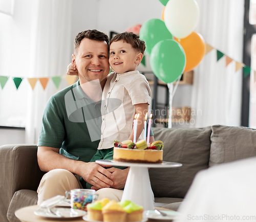 Image of happy father and son with birthday cake at home