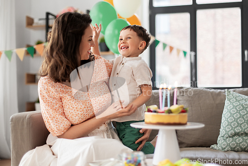 Image of happy mother and son with birthday cake at home