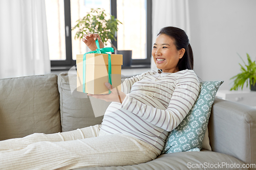 Image of happy pregnant woman with gift box at home