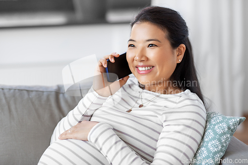 Image of happy pregnant woman calling on smartphone at home