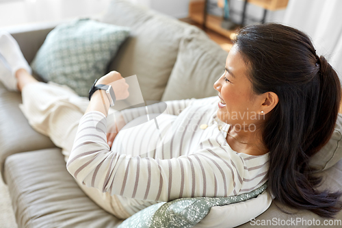 Image of happy pregnant woman with smart watch at home