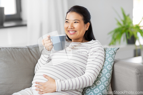 Image of happy pregnant woman drinking tea at home