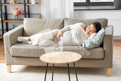 Image of pregnant asian woman sleeping on sofa at home