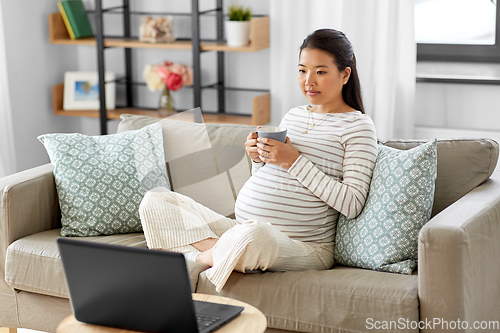 Image of pregnant asian woman with laptop at home