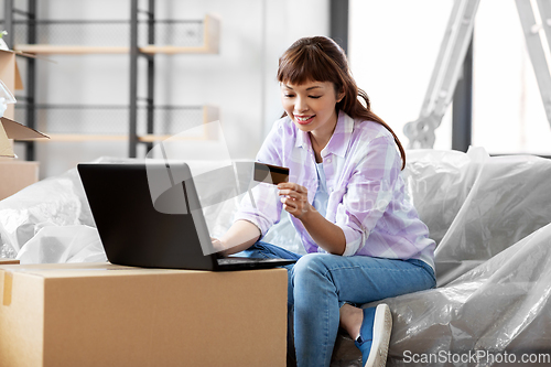 Image of woman with laptop and credit card at new home