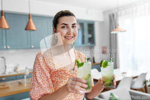 Image of woman with lime mojito cocktail at home kitchen