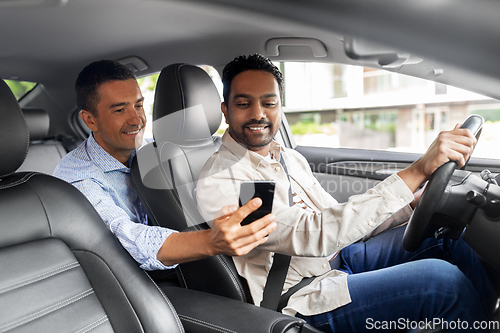 Image of male passenger showing smartphone to car driver