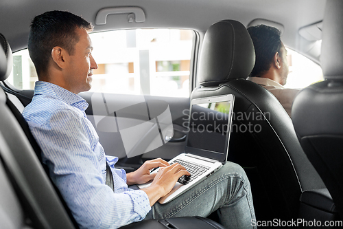 Image of male passenger with laptop computer in taxi car