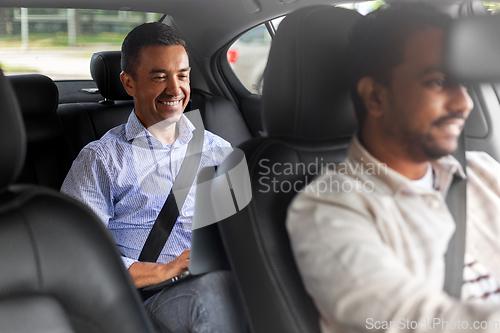 Image of male passenger with laptop computer in taxi car