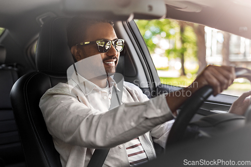 Image of smiling indian man in sunglasses driving car