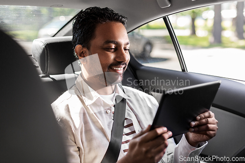 Image of indian male passenger with tablet pc in taxi car