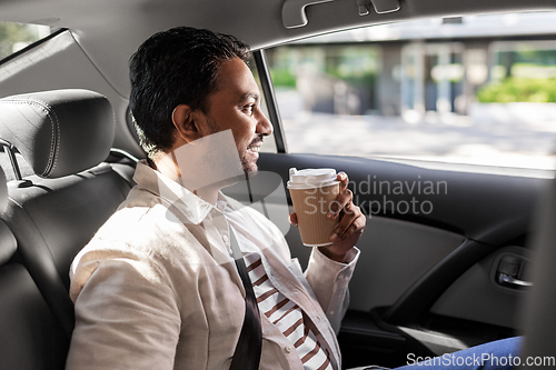 Image of indian man with takeaway coffee on car back seat