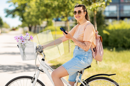 Image of woman with smartphone on bicycle in city