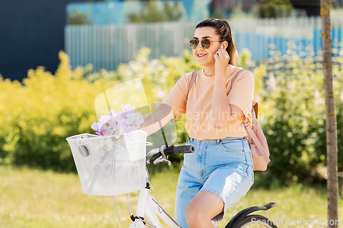 Image of happy woman with earphones riding bicycle in city