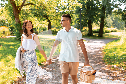 Image of happy couple with picnic basket at summer park