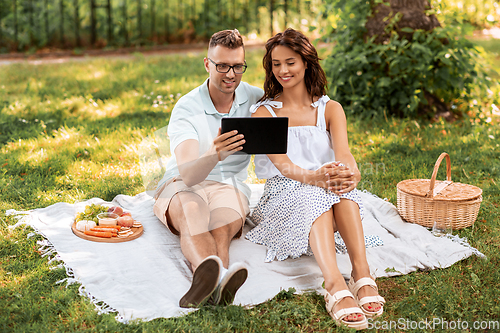 Image of happy couple with tablet pc at picnic in park