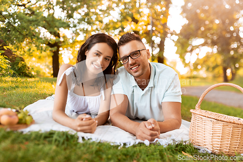 Image of happy couple on picnic blanket at summer park