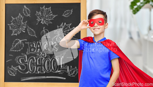 Image of boy in super hero costume over school blackboard