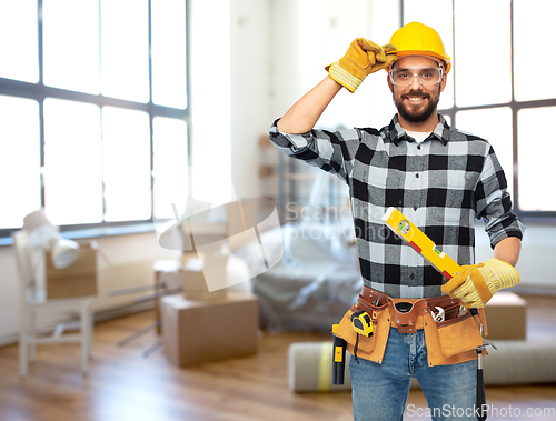 Image of happy male builder in helmet with level at home