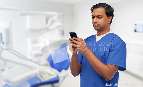 Image of indian doctor using smartphone at dental office