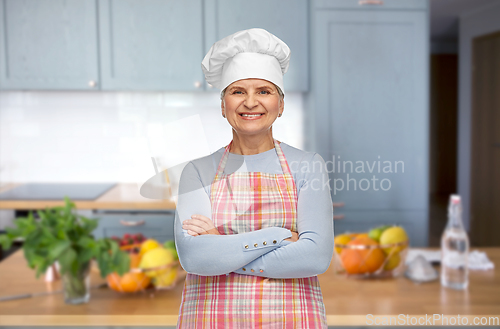 Image of smiling senior woman or chef in toque at kitchen