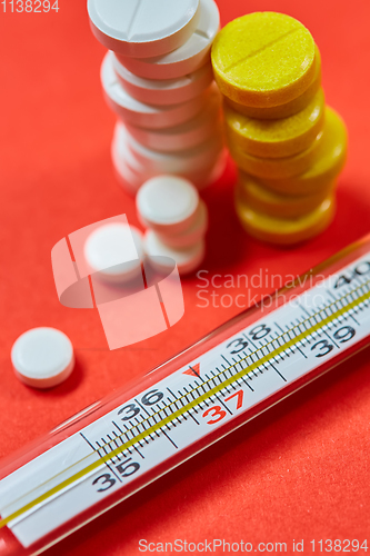 Image of Mercury thermometer and medical pills on background