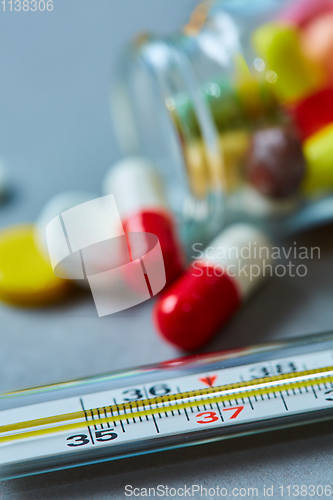 Image of Mercury thermometer and medical pills on background