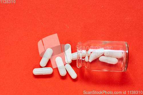 Image of Pills spilling out of pill bottle on red. Top view with copy space. 