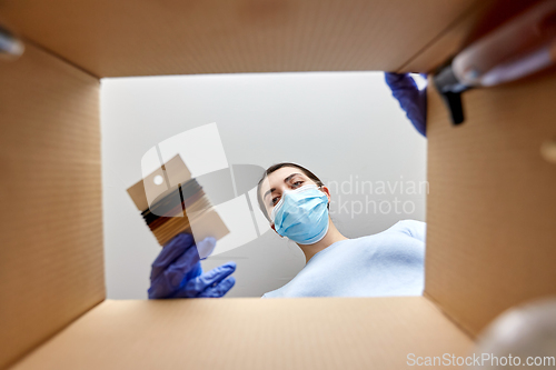 Image of woman in mask unpacking parcel box with hair bands