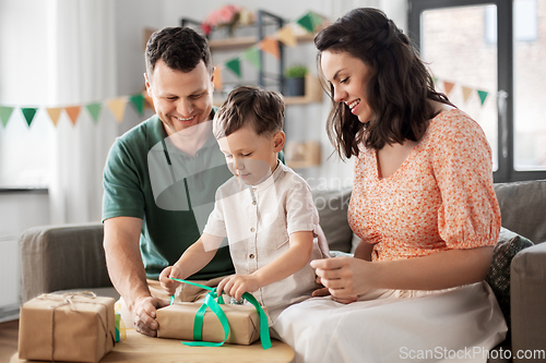 Image of happy family opening birthday presents at home