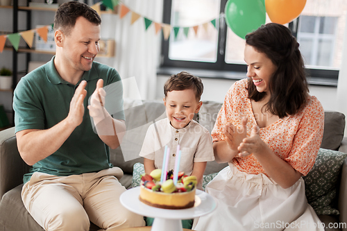 Image of happy family with birthday cake at home