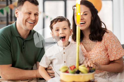 Image of happy family with birthday cake at home