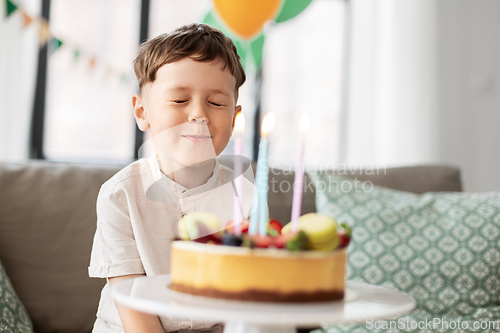 Image of little boy with birthday cake making wish