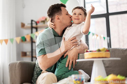 Image of father kissing little son at home birthday party