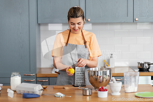 Image of happy young woman cooking food on kitchen at home