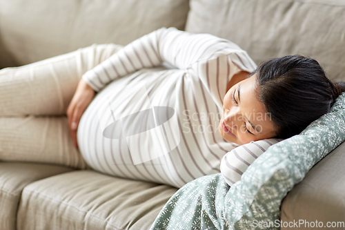 Image of pregnant asian woman sleeping on sofa at home