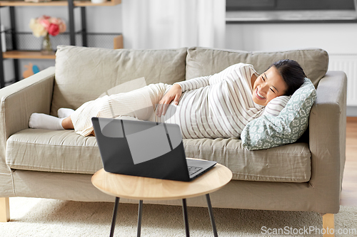 Image of happy pregnant asian woman with laptop at home