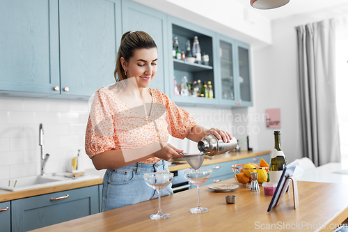 Image of woman with tablet pc making cocktails at kitchen