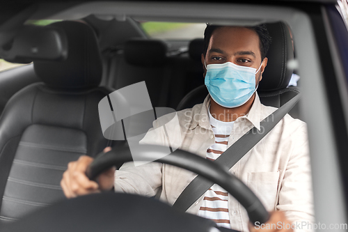 Image of indian male driver in mask driving taxi car