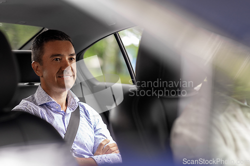 Image of smiling middle aged male passenger in taxi car