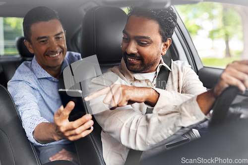 Image of male passenger showing smartphone to car driver