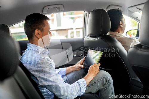 Image of male passenger with tablet computer in taxi car