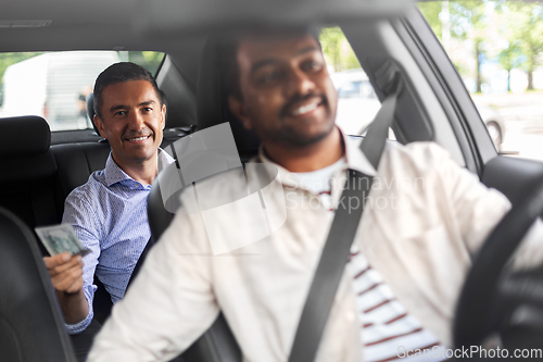 Image of smiling passenger giving money to taxi car driver
