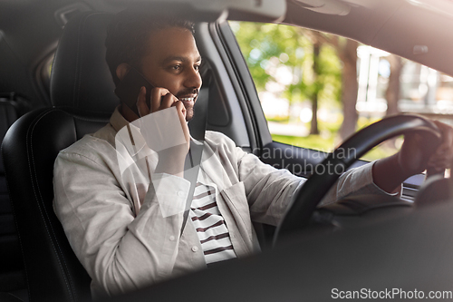 Image of indian man driving car and calling on smartphone