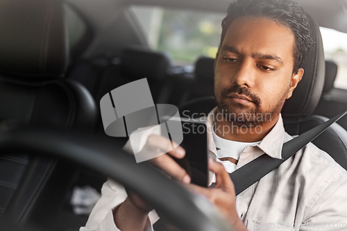Image of indian man in car using smartphone