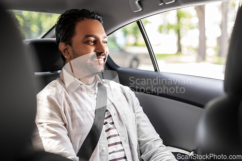 Image of smiling indian male passenger in taxi car