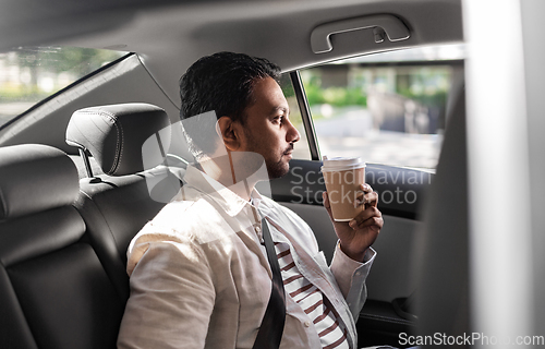 Image of indian man with takeaway coffee on car back seat