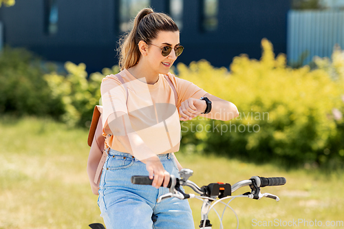 Image of woman with smart watch riding bicycle in city