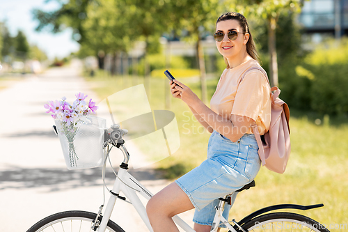 Image of woman with smartphone on bicycle in city