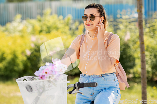 Image of happy woman with earphones riding bicycle in city